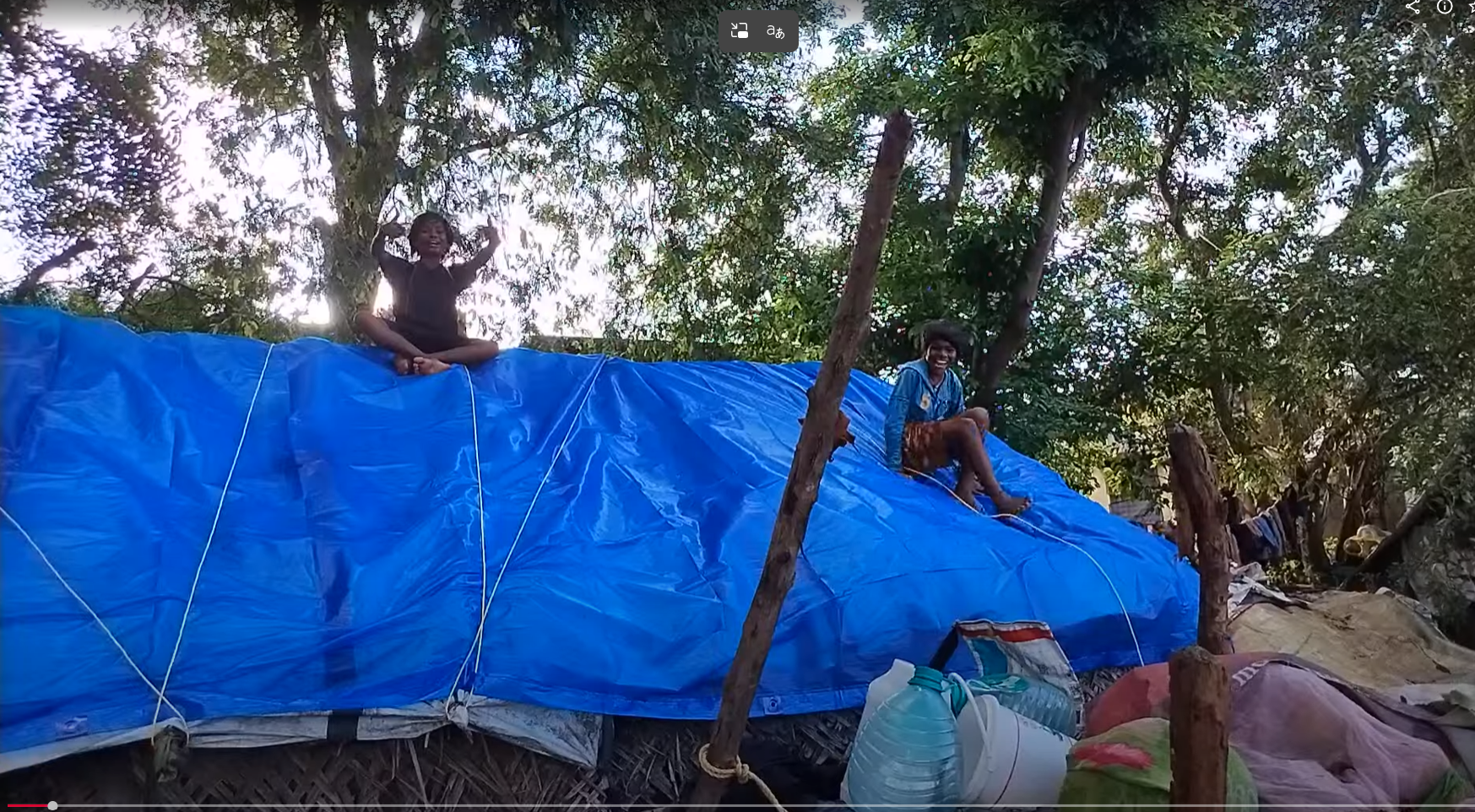 Children sitting on rain tarp shelter in Pondicherry
